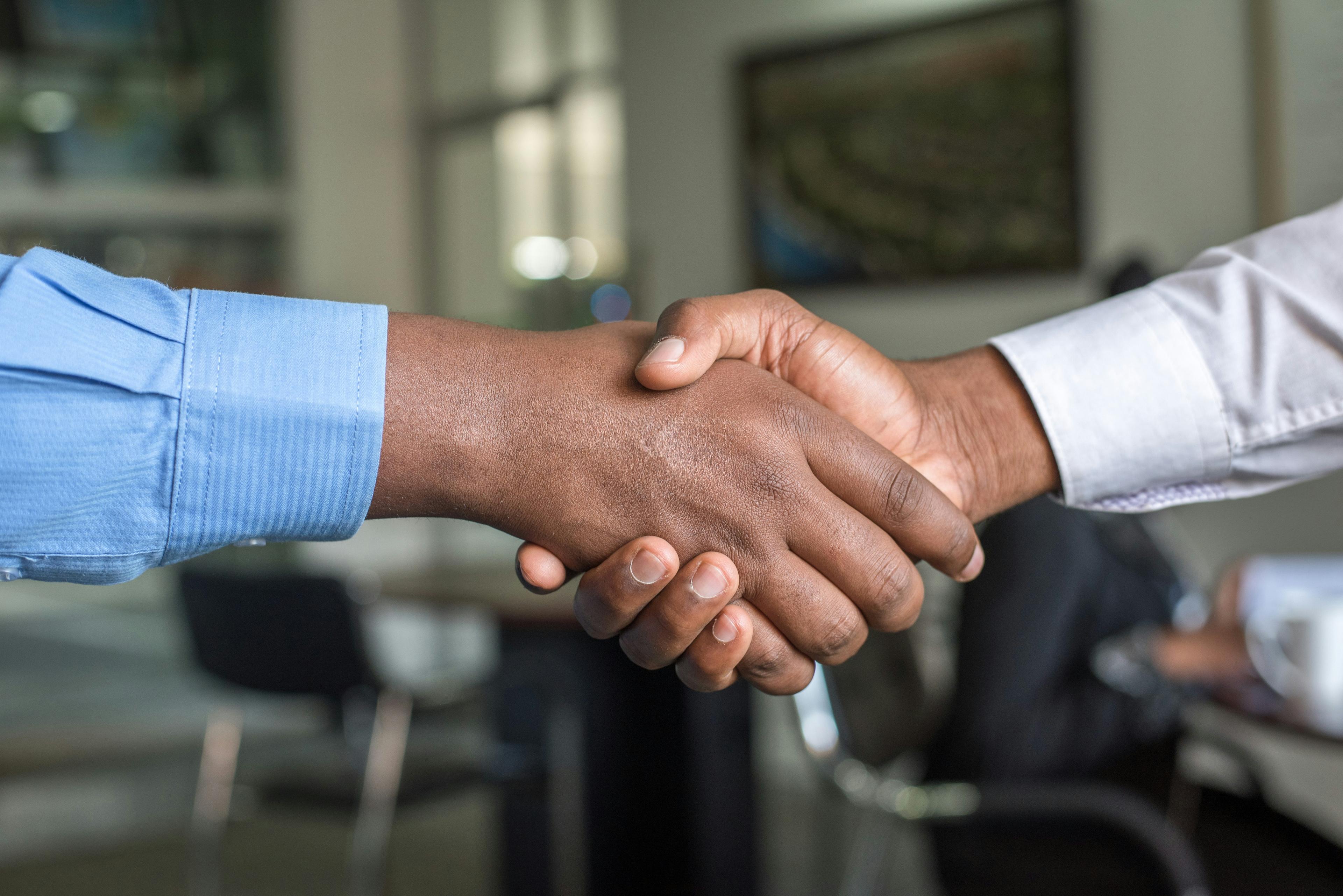 Two business professionals shaking hands over a signed agreement