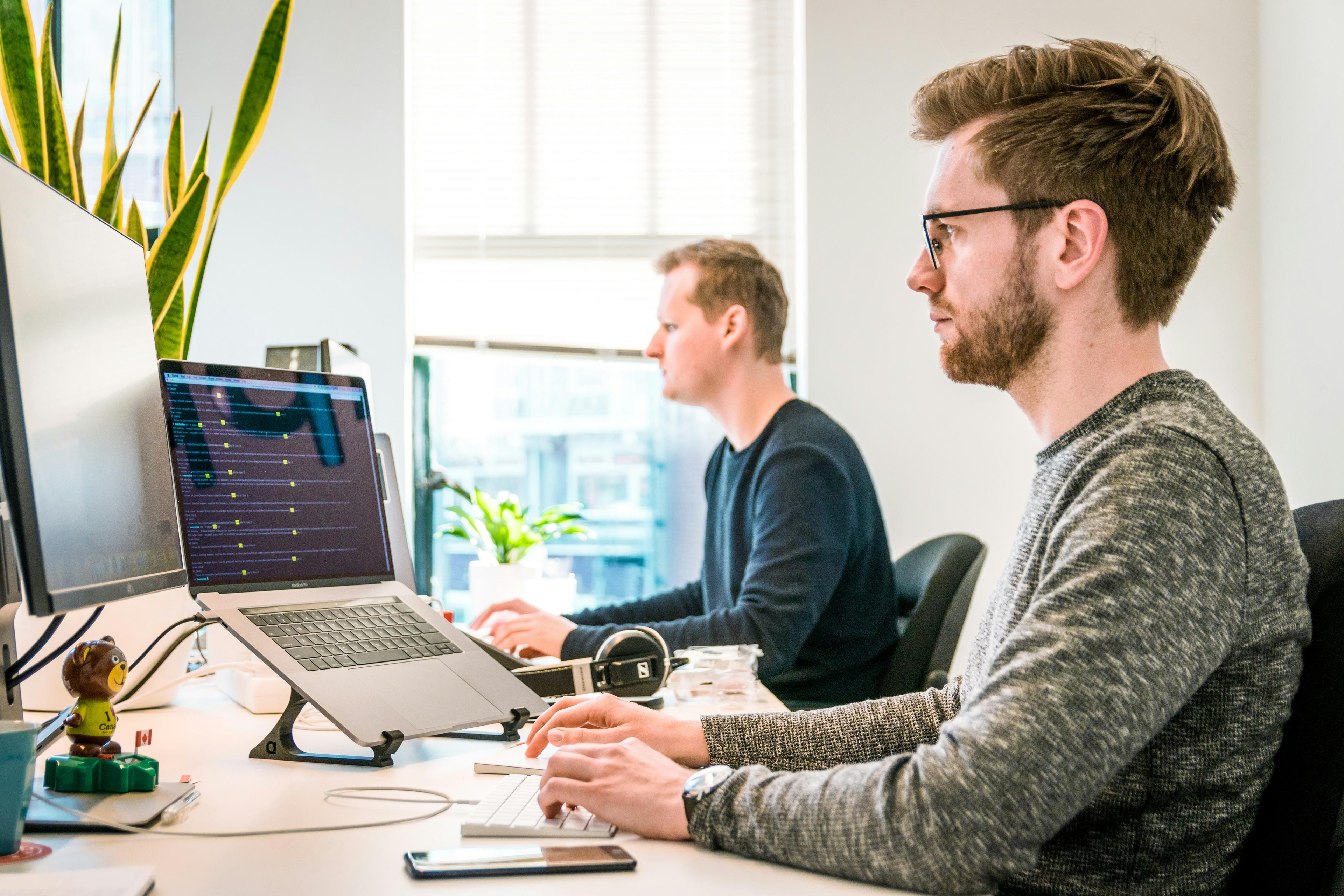 Two B2B sales professionals reviewing lead scoring dashboards on laptops in a modern office