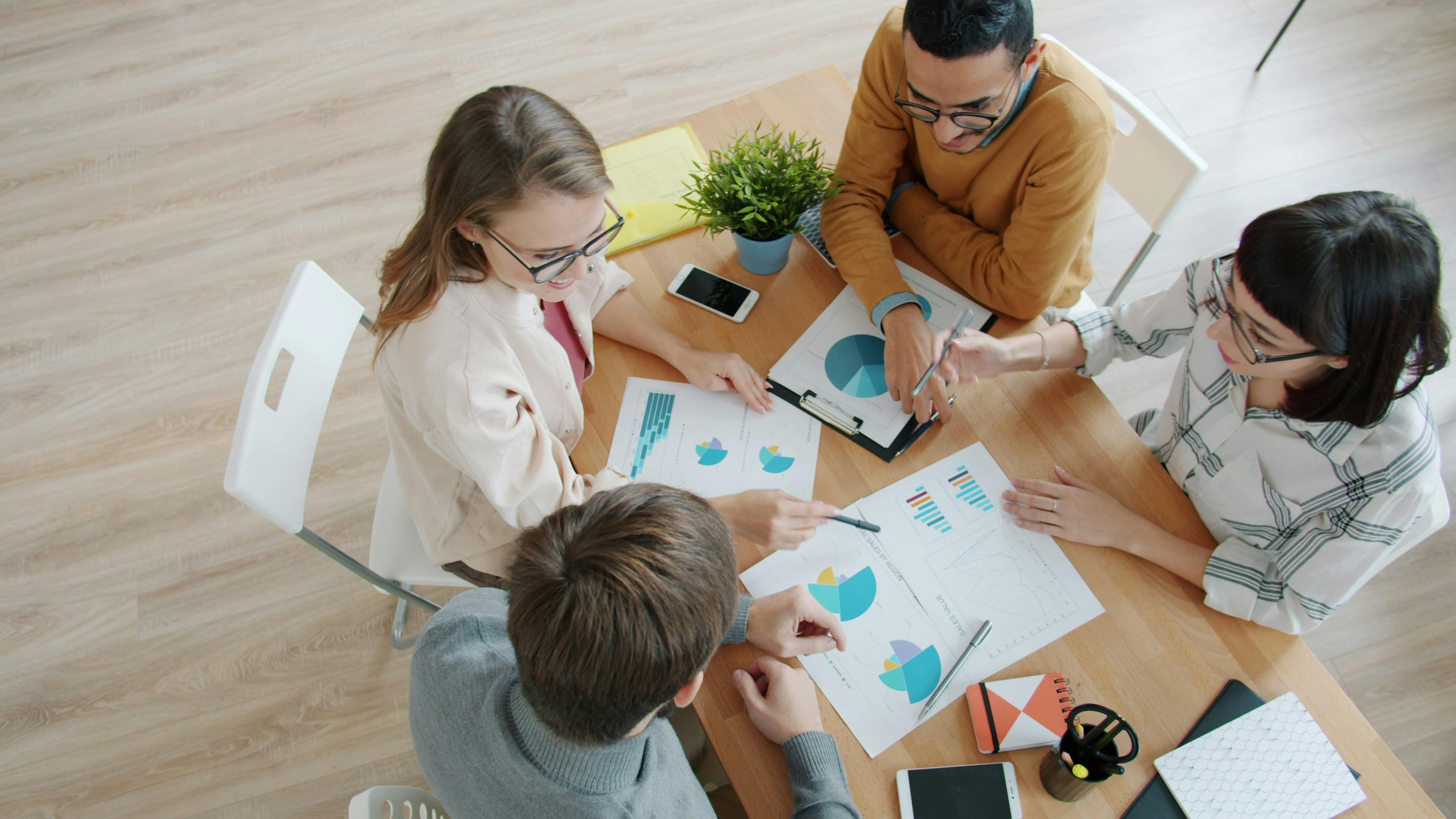 B2B sales team reviewing win loss analysis charts and deal data around a table
